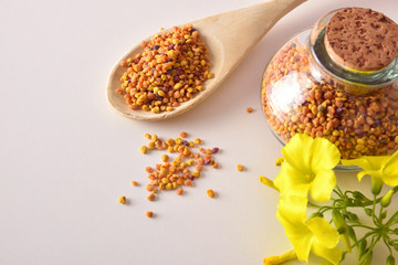 Grains of bee pollen in jar and wooden spoon top