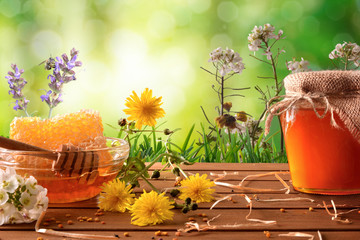 Honey pot and honeycomb with green nature background with flowers