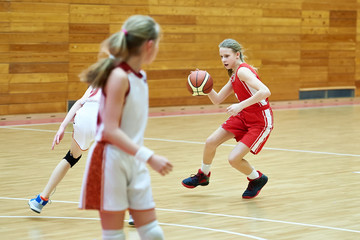 Girls in sport uniform playing basketball indoors