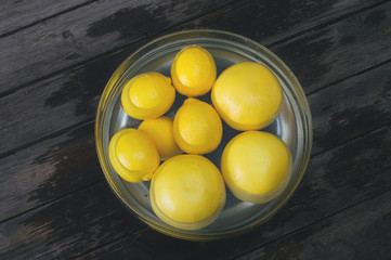 A bunch of lemon and grapefruit in a bowl full of water. Selective focus and small depth of field.