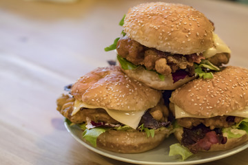 Chickenburgers with cheese, bacon and salad on a plate
