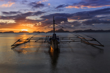 Cruise boat standing still on water with sunset in background, Palawan, Philippines