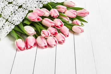 Bouquet of pink tulips, white tablecloth. Top view, copy space