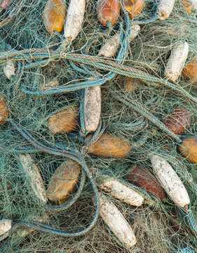 Detail image of tangle of fishing net and floats left lying on dock side.