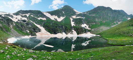 Mountain Lake with clean water in the Caucasus summer. Blue sky with white clouds.
