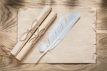 Medieval parchment paper scrolls feather on wooden board