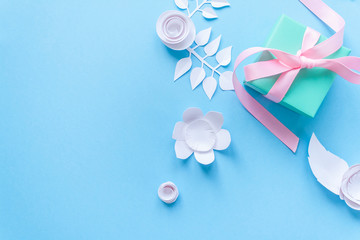 a gift and white paper flowers on blue background