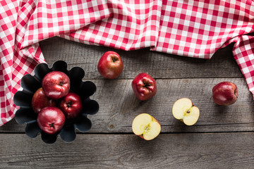 Ripe red apples in baking form on wooden board with red checkered napkin.