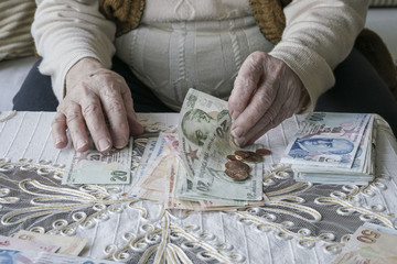 Wrinkled hands counting Turkish Lira banknotes