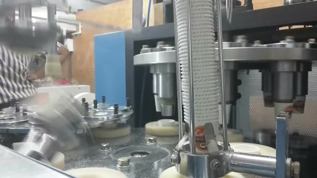 Industrial Paper cups being manufactured in machine, high speed production from rotating machine parts, HD footage of automated machinery
