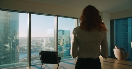 Young business woman is part of a modern office skyscraper in talks on the phone, steadicam shot