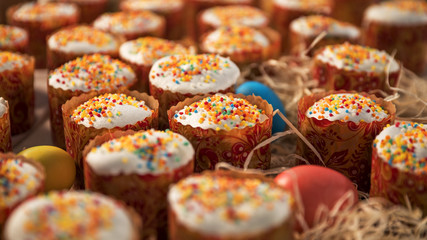 A large number of festive cakes laid out on the table, next to lay colored eggs