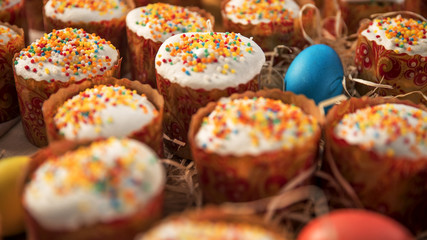 A large number of festive cakes laid out on the table, next to lay colored eggs