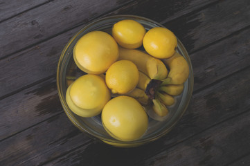 A bunch of fresh yellow fruit in a bowl full of water. Selective focus and small depth of field.