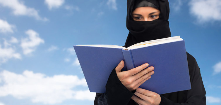 muslim woman in hijab reading book over sky