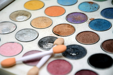 Close up view of eyes shadow color palette with two brushes.