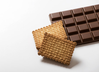 Tablet of chocolate with milk next to cookies on white background. Copy-space. Horizontal shoot...