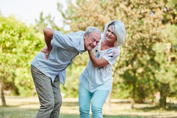Frau hilft altem Mann mit Rückenschmerzen