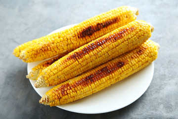 Tasty grilled corn on grey wooden table