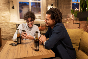 men with smartphones drinking beer at bar or pub