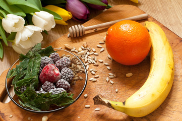 Fototapeta na wymiar banana, orange,frozen strawberries blackberries and seeds vivid smoothie ingredients on the background