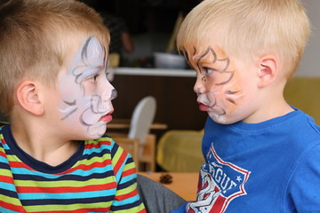 Two boys with painted faces talking to each other