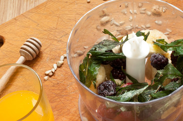 cooking, orange juice, banana,frozen strawberries blackberries and seeds vivid smoothie ingredients in blender, juicer, tulips on the background