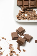 Tablet and chocolate pieces on white tray. Isolated. Horizontal shoot.
