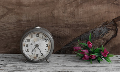 vintage alarm clock and flowers on old wooden background