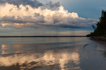 Beautiful sunset on the lake, the clouds reflected in the water. Surface on the lake. Russia, Karelia. Wide photo