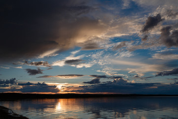 Beautiful sunset on the lake, the clouds reflected in the water. Surface on the lake. Russia, Karelia. Wide photo