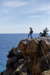 Photographer enjoying seaview and standing on high rock cliff