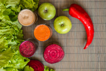 three glasses of different fresh juice. Beet, carrot and apple juices on grey wood background