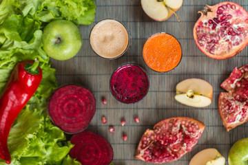 three glasses of different fresh juice. Beet, carrot and apple juices on grey wood background