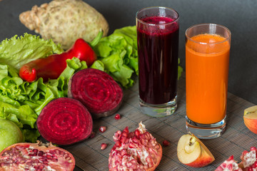 two glasses of different fresh juice. Beet and carrot juices on grey wood background