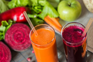two glasses of different fresh juice. Beet and carrot juices on grey wood background
