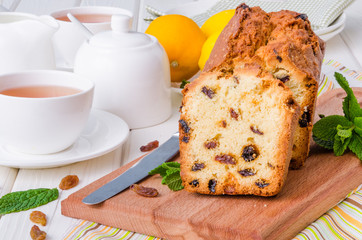 Lemon pound cake with dried cranberries and raisins on white wooden background