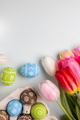 Painted easter eggs and bouquet of spring tulips closeup on a light blue background with space for congratulation