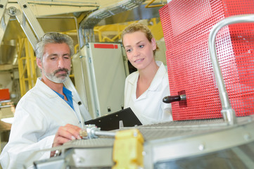 Obraz premium Two technicians taking reading from machine