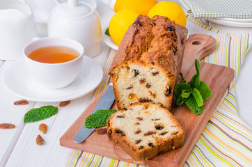 Lemon pound cake with dried cranberries and raisins on white wooden background