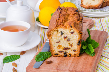 Lemon pound cake with dried cranberries and raisins on white wooden background