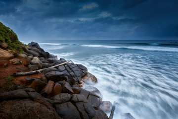 Beautiful stormy sunset with rocks and ocean