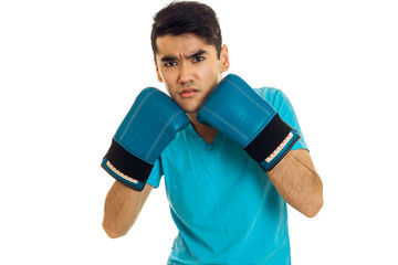 portrait of strong sportsman with dark hair practicing boxing in blue gloves and uniform isolated on white background