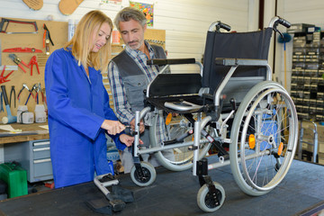Obraz premium Man and woman with wheelchair on workshop bench