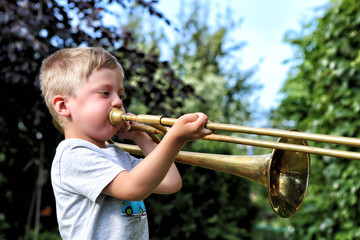 Profile of the small boy trying to play trombone