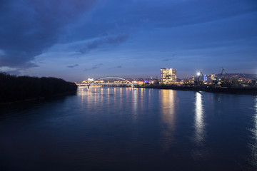 Naklejka premium Old town, riverside, Bratislava castle, Apollo Bridge, UFO Bridge, New Bridge shoot during dusk from above river Danube, Slovakia