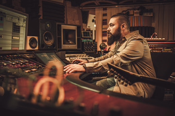 Sound engineer and guitarist recording song in boutique recording studio.
