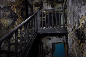 Fototapeta na wymiar Interior of the burned by fire house, burned wooden stairs