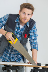 portrait of carpenter working with a saw at construction site