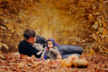 Молодой отец играет со своей маленькой дочерью в осеннем лесу